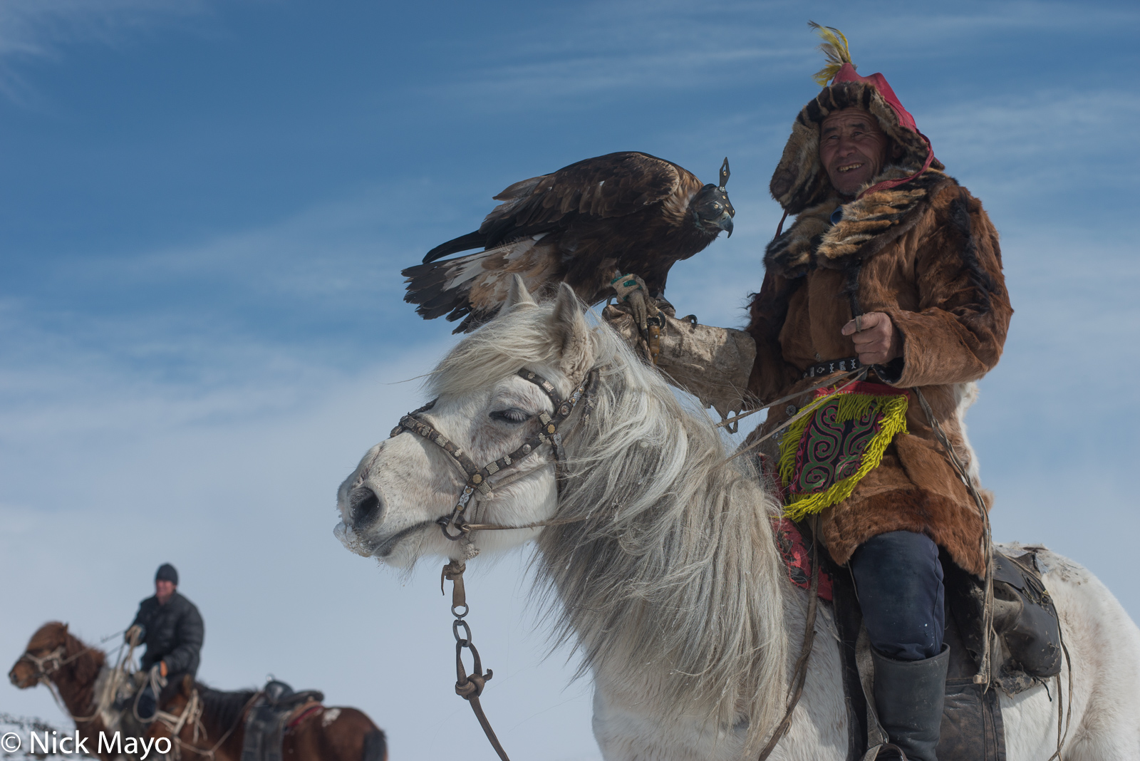 A Kazakh eagle hunter in Ulaakhus sum on horseback holding his hooded bird.