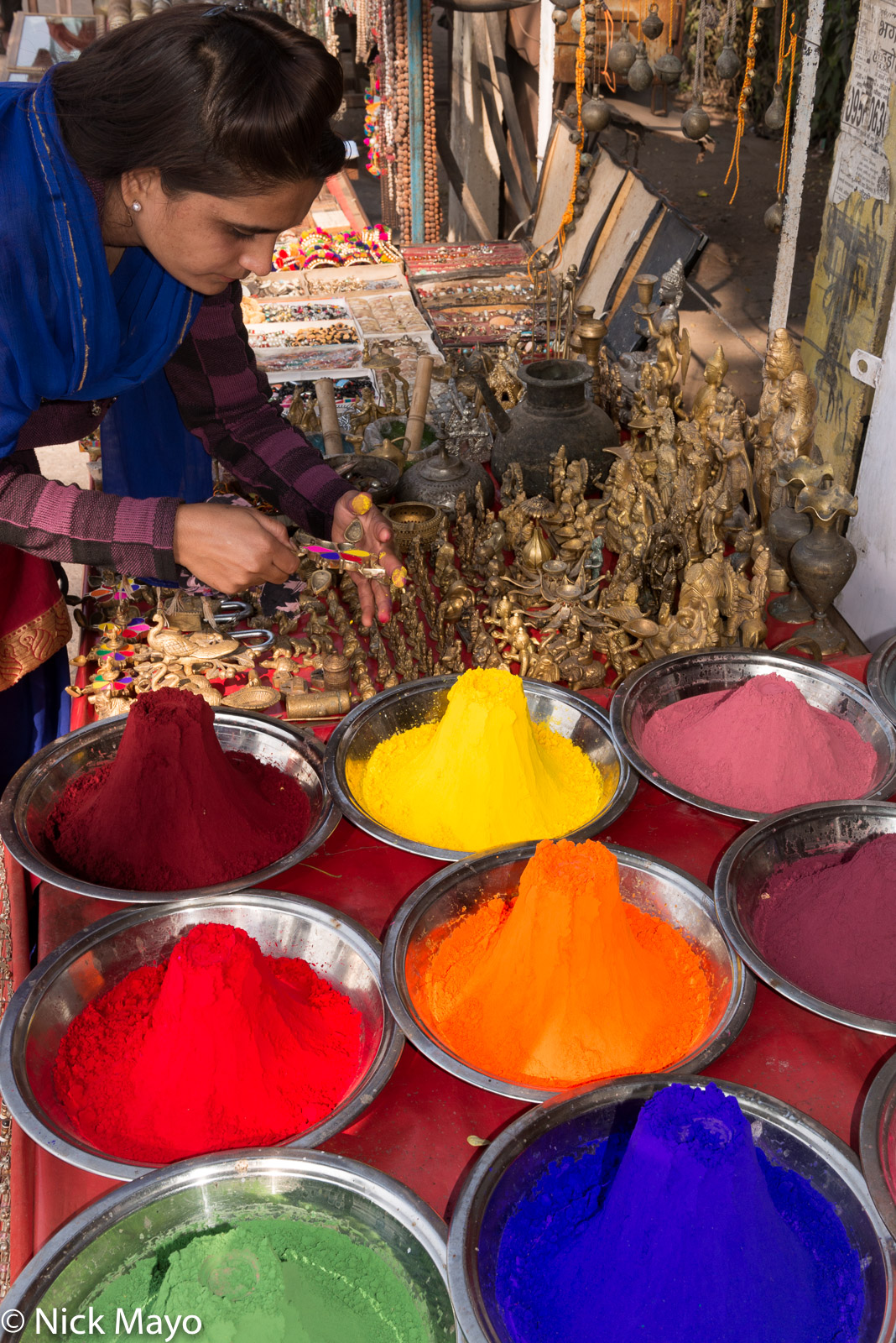 A shop vendor filling a local style compact with kumkum powder at Orchaa.