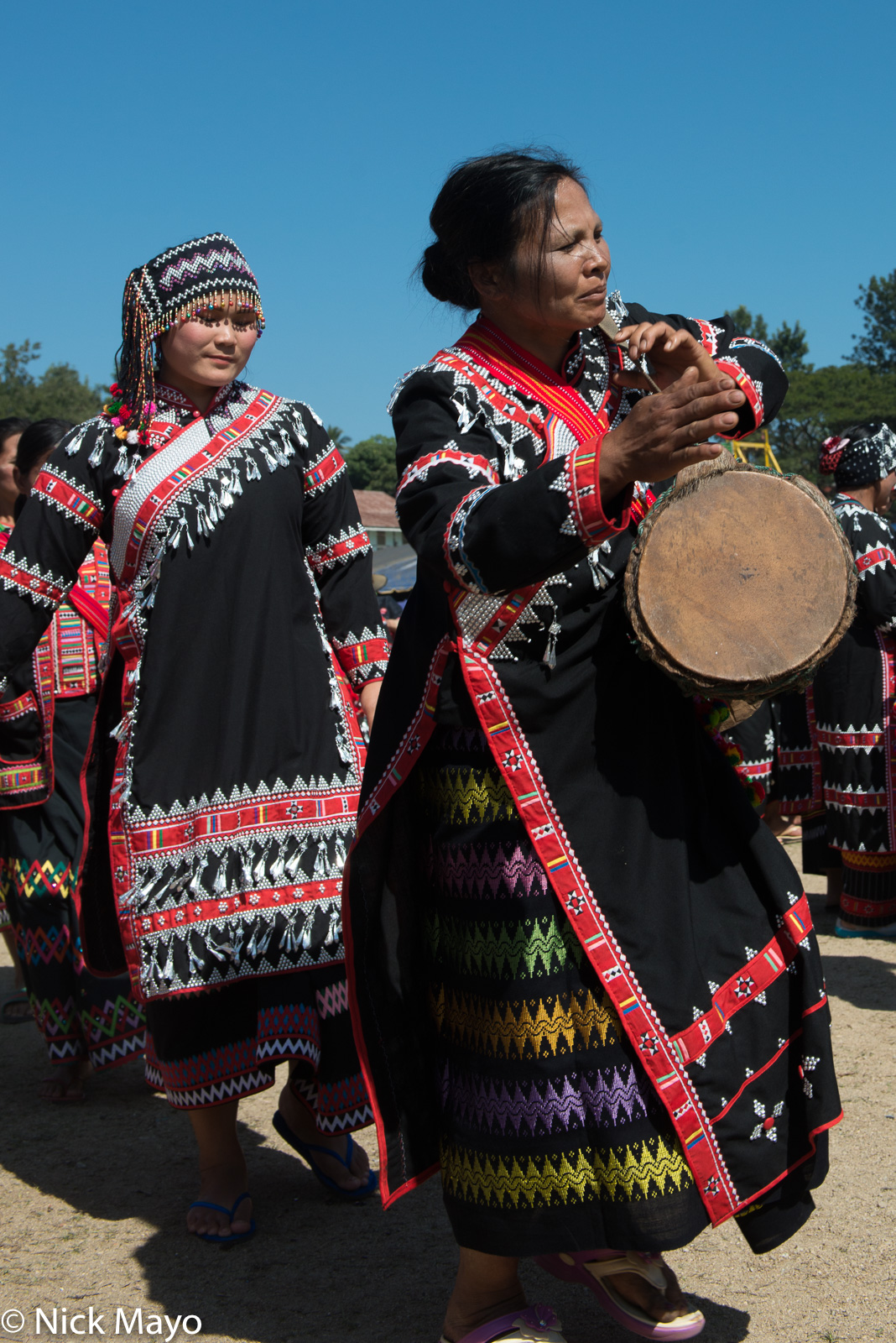 A Black Lahu woman drumming on a frame drum at her New Year festival in Kengtung.