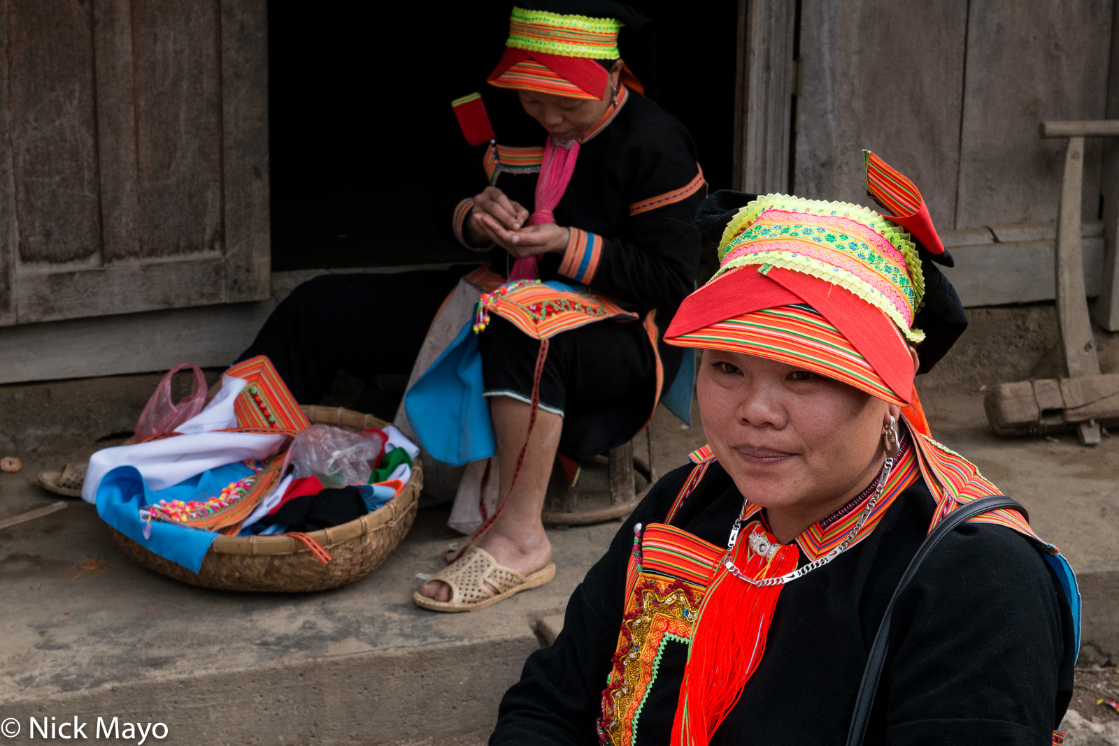 Two Black Dao women, one sewing, in Pocha village.
