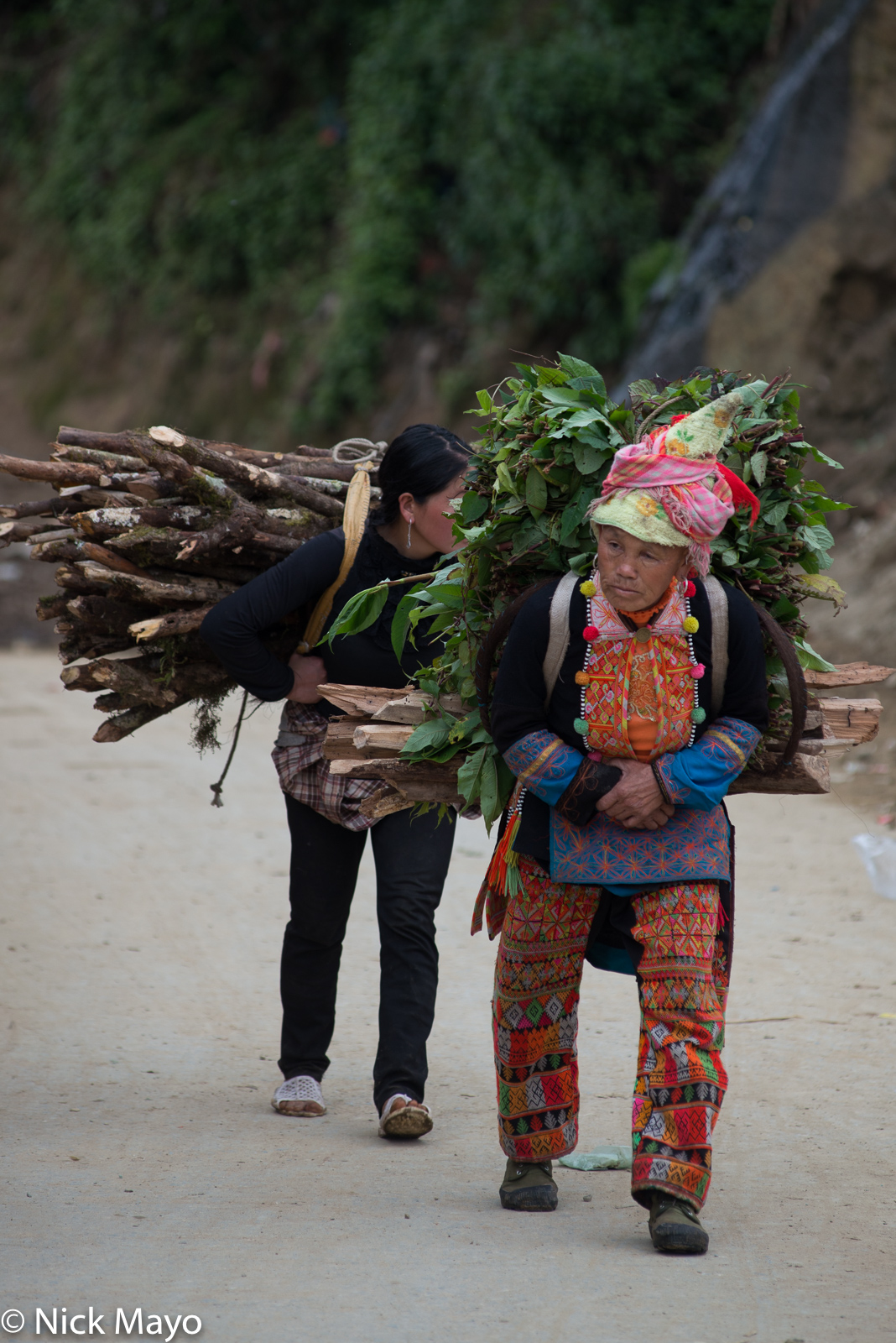 Two Dao women using straps to carry home fodder and firewood at Si Lo Lau.