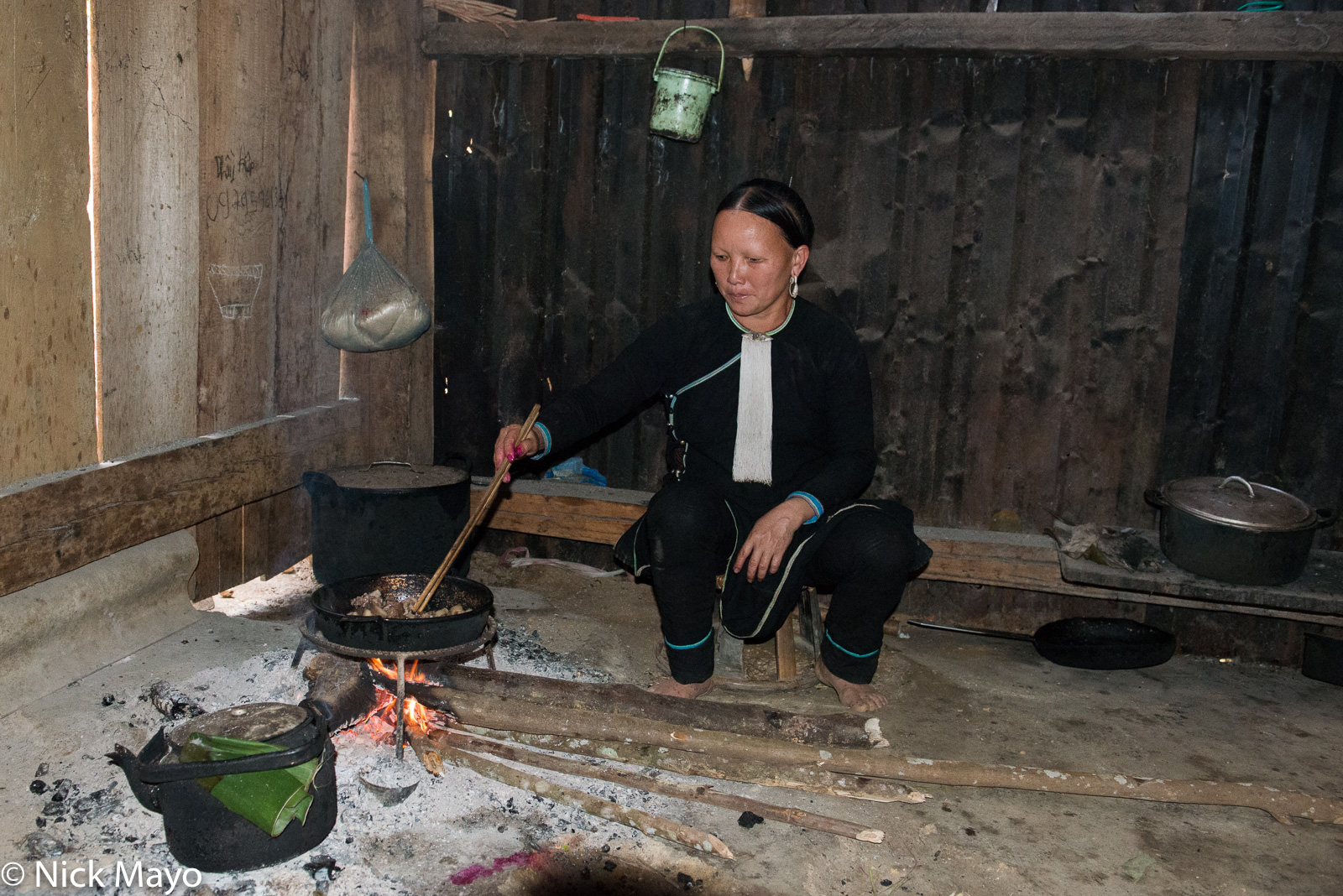 A Dao woman cooking meat on an open hearth in her house in the Nam Ma valley.