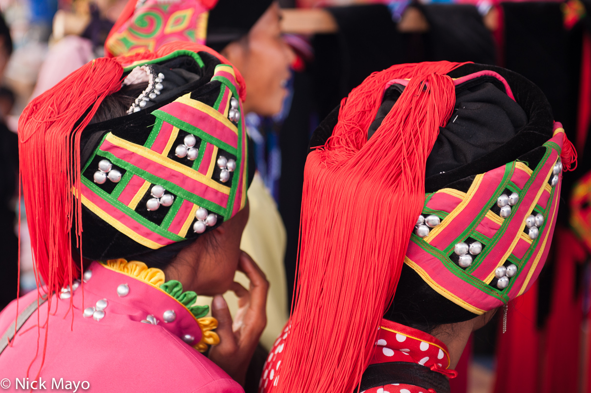 Two Hani woman in traditional red tassled hats in Da Hei Shan market.