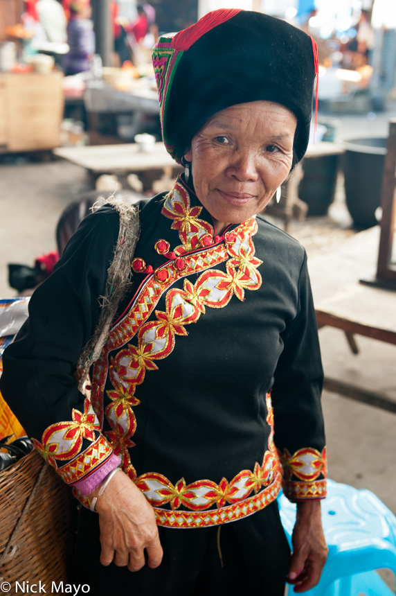 A Hani woman in traditional clothes and hat at Da Hei Shan market.