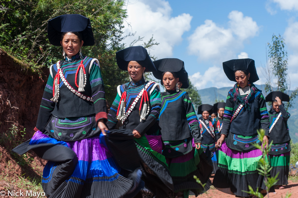 A group of greeters, wearing traditional clothes, hats, necklaces and earrings, on their way to a funeral at Mi Shi Qing Mo in...