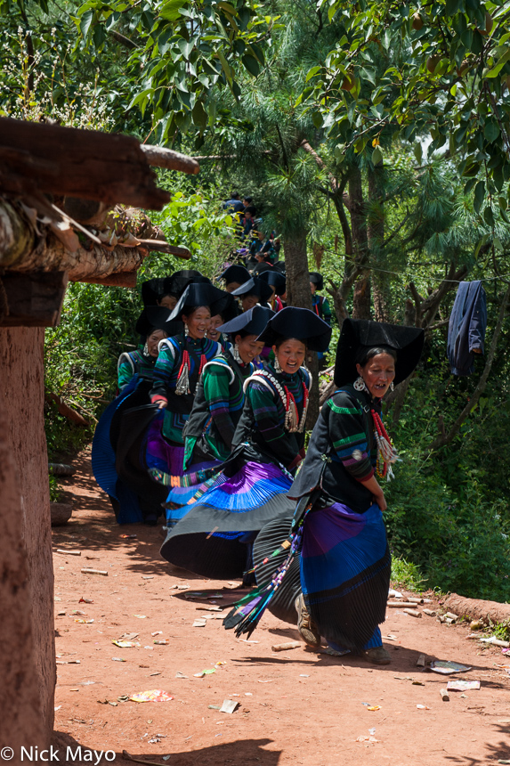 A female greeter performing a skirt swirl while heading to a Yi funeral at Mi Shi Qing Mo in Daliangshan.