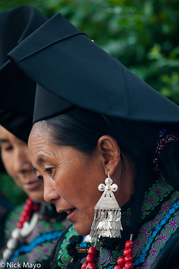 A Yi woman, wearing a traditional hat and pendant earring, at a festival in the Daliangshan village of Hubo Luo.