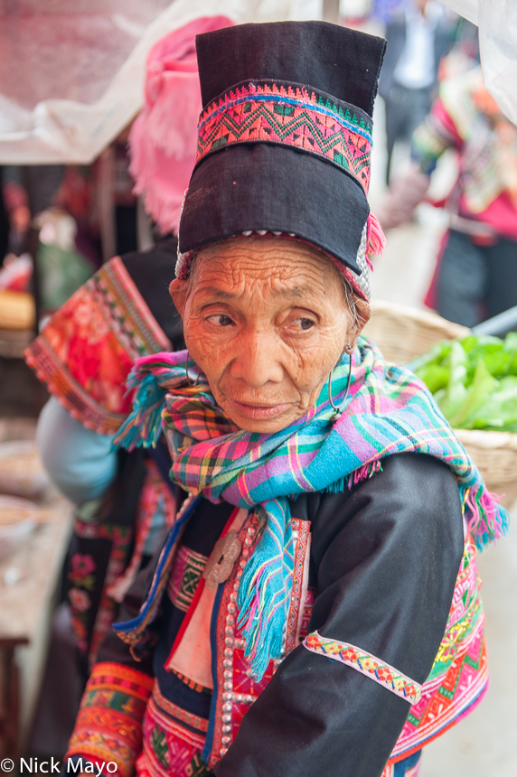 A Dai woman wearing a traditional hat and earrings at Majie market.