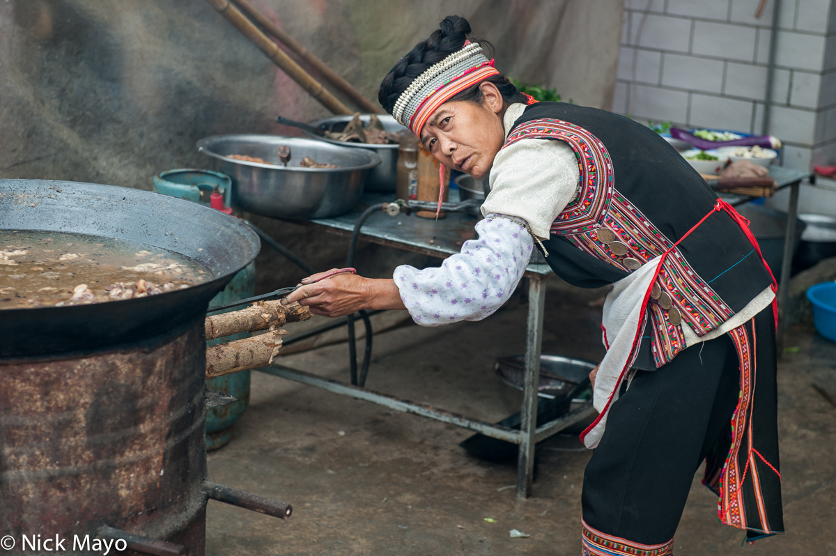 A Hani woman cooking on a wok at Majie market.