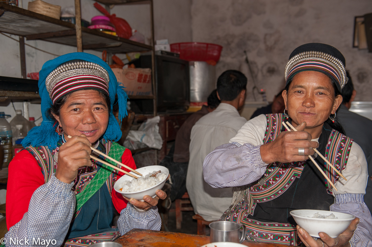 Two Hani women eating rice in a market restaurant at Majie.