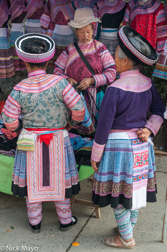 Miao women in traditional hats shopping at Baihe market.