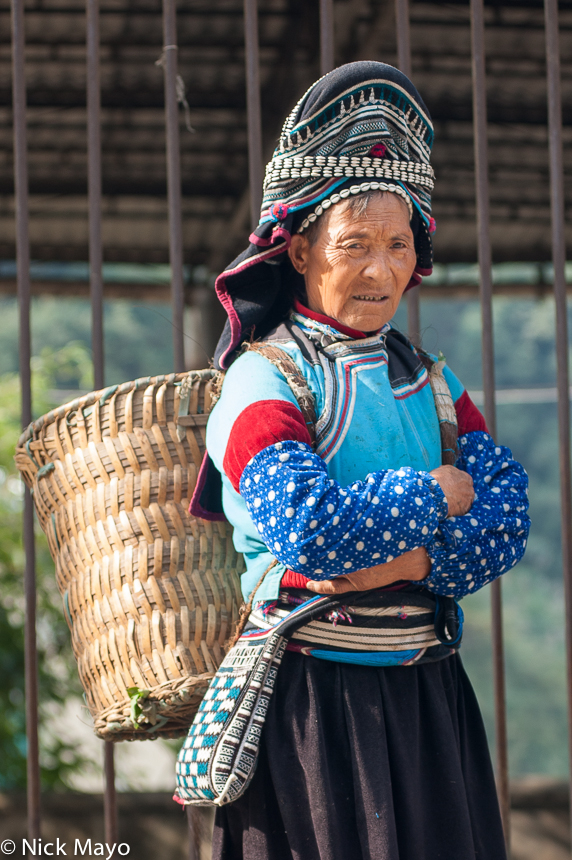 A Pupao Yi woman carrying a basket at Baihe market.