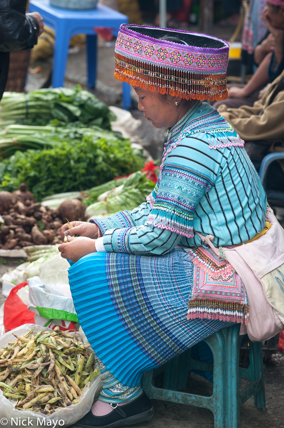 A Miao woman shelling beans in Baihe market.