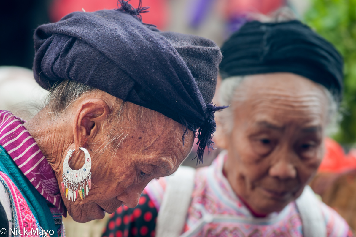 An older Miao woman wearing a turban and earrings in Baihe.