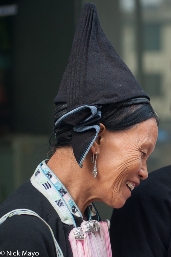 A Yao woman from the Meng Chiao area wearing a peaked black hat .