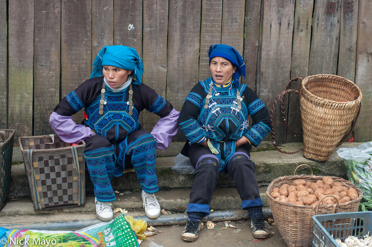 Two Hani woman, with their baskets, selling vegetables at Maandi market.