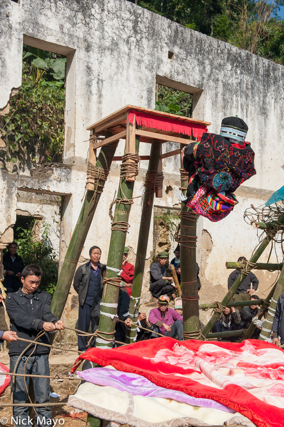 An initiate falling backwards from a platform into a blanket covered vine net during a dujie ceremony in the Yao village of Ku...