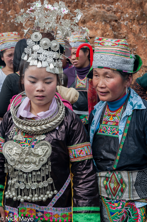 A newly wed bride, in headdress, breastpiece and necklace, with an older lady in Yangweng.