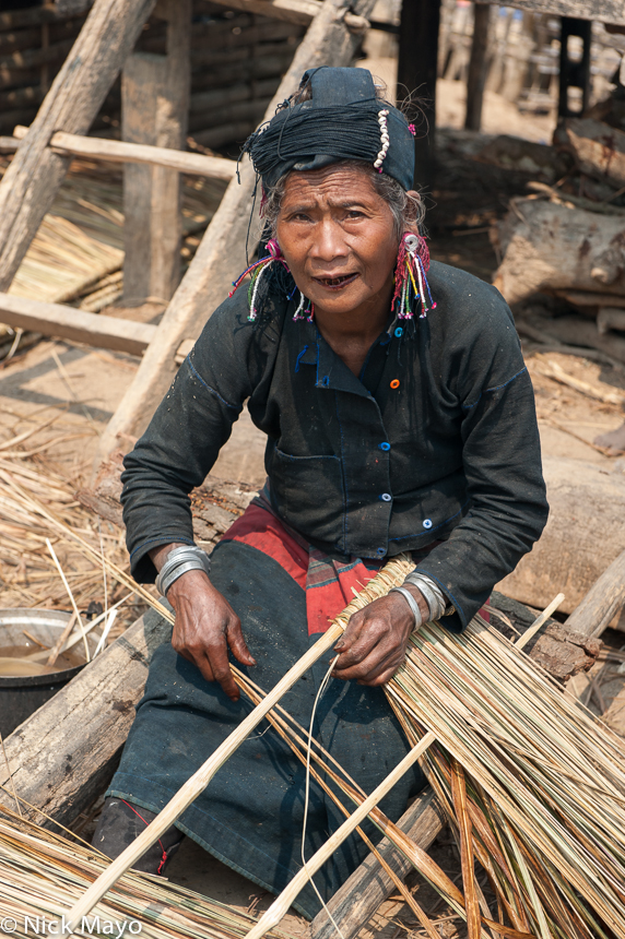 An Eng women with betel stained teeth preparing thatch at Ban Nong village.