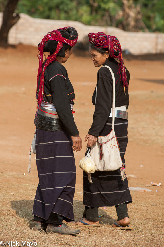 Two traditionally attired Paluang women holding a passing conversation at Loilom monastery on a shinbyu (novitiation) day.