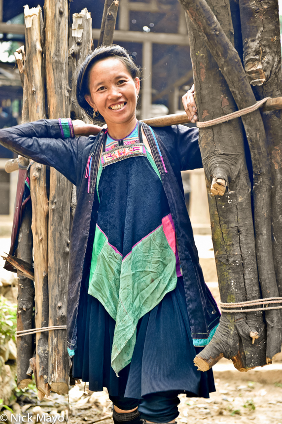 A Dong women using a shoulder pole to carry home firewood to Wuei village.
