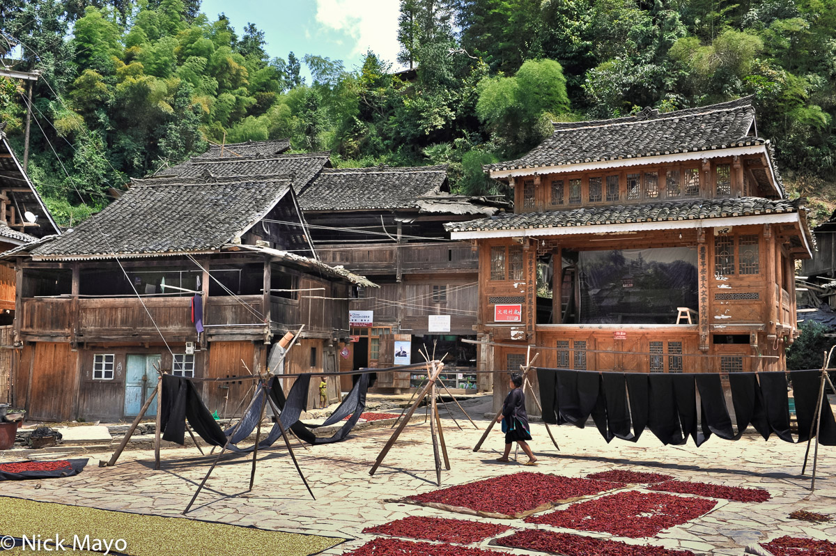 Chillies and freshly indigo dyed cloth drying in front of the opera stage at the Dong village of Yintan.