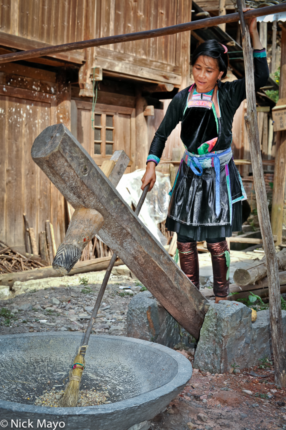A Dong woman hulling paddy rice with a foot levered huller in Yintan.