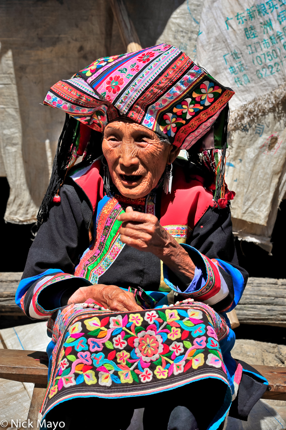 A traditionally attired Lisu woman sporting long earrings and wearing an embroidered apron and turban in the village of Huang...