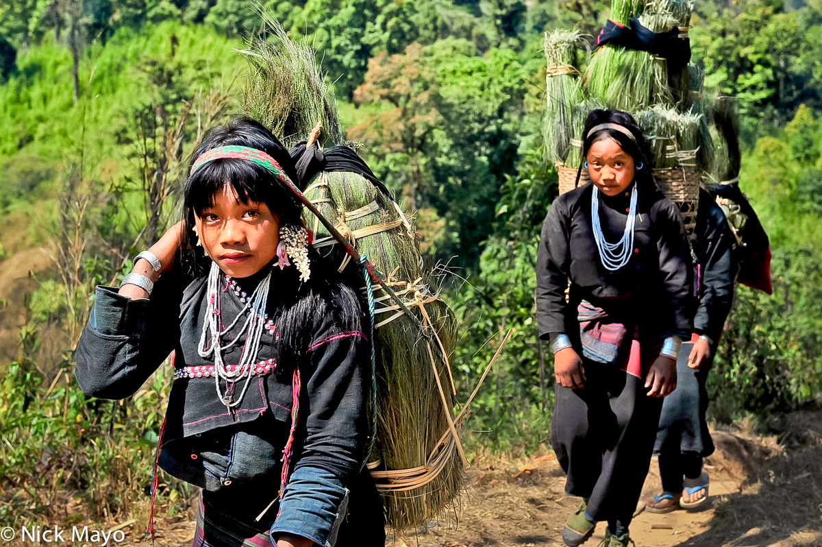 Eng girls heading down the mountain from Ban Nong carrying loads of cut grass by head strap.