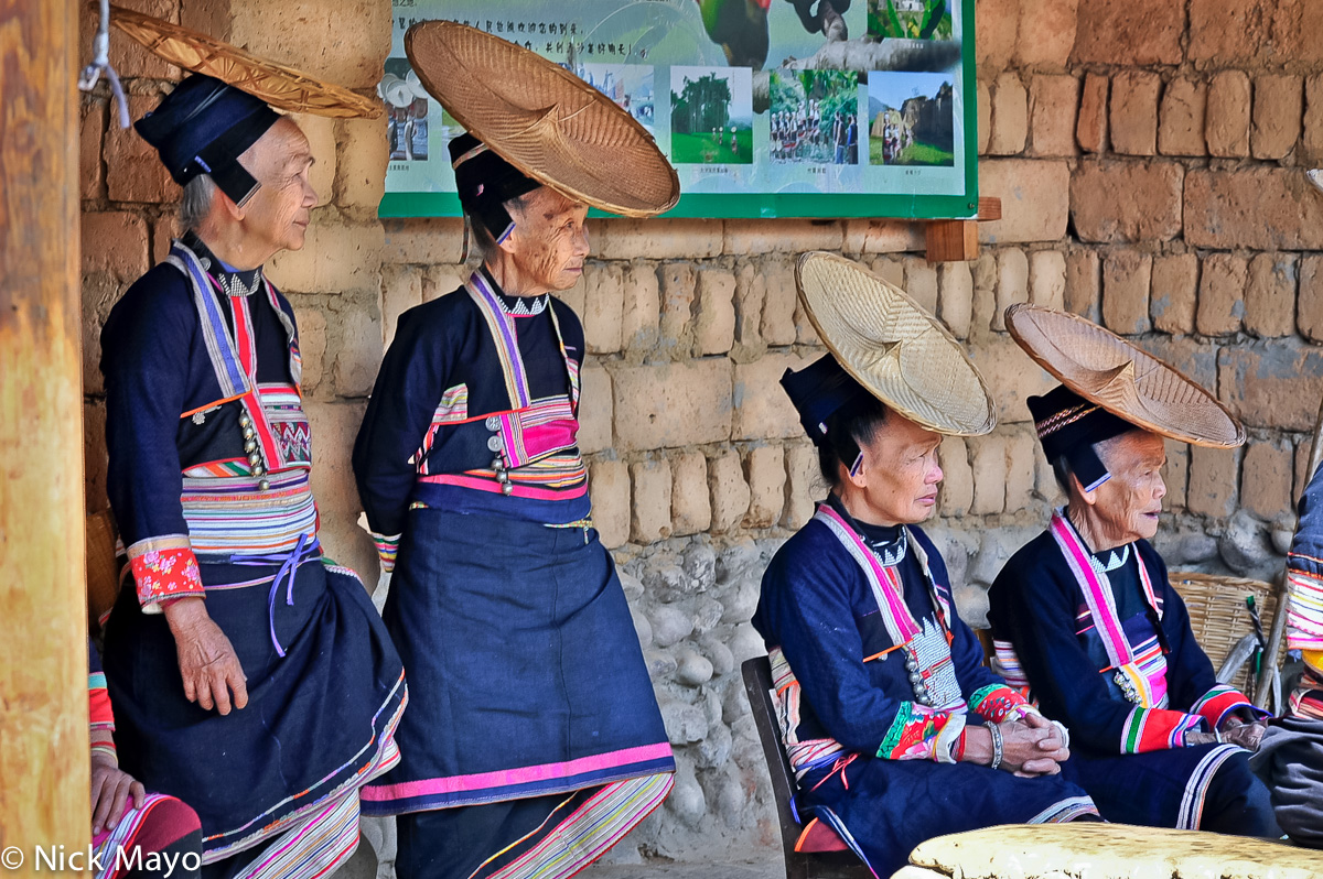 Four Hua Yao Dai women wearing traditional clothes, hats and breastpieces observing a festival in Mosha.
