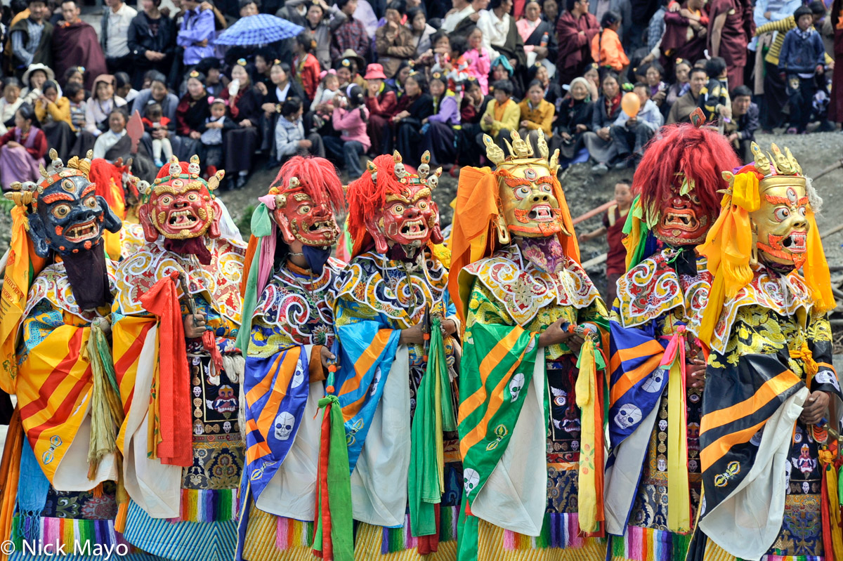 Masked Tibetan monks waiting to dance at a festival at the Katok monastery.