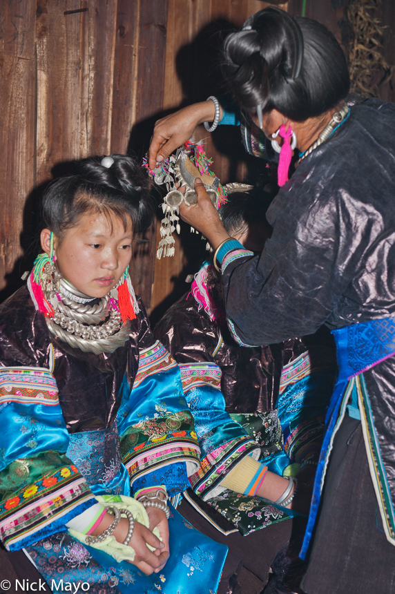 A Miao bride having her hair piece symbolically removed by her mother after the wedding ceremony in the village of Gui Lai.