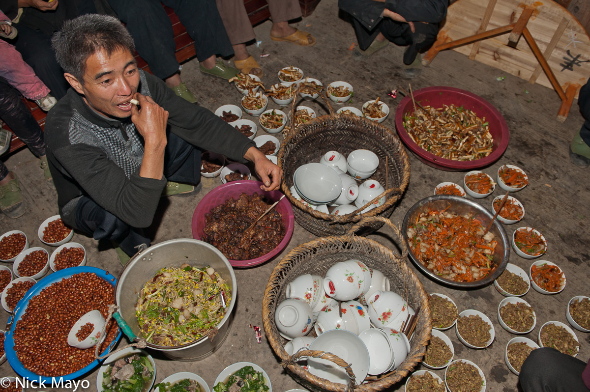 A Miao man preparing vegetable dishes for a wedding banquet in the village of Gui Lai.