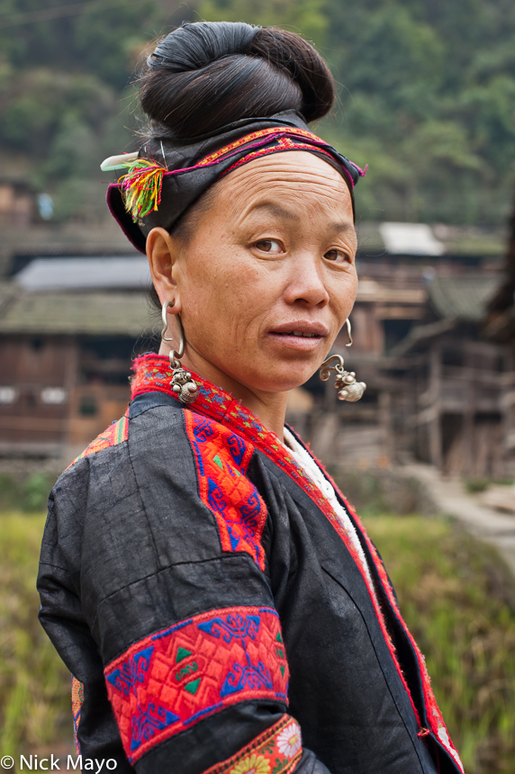 A woman with a traditional hairstyle and pendant earrings in the Miao village of Ba Shu.