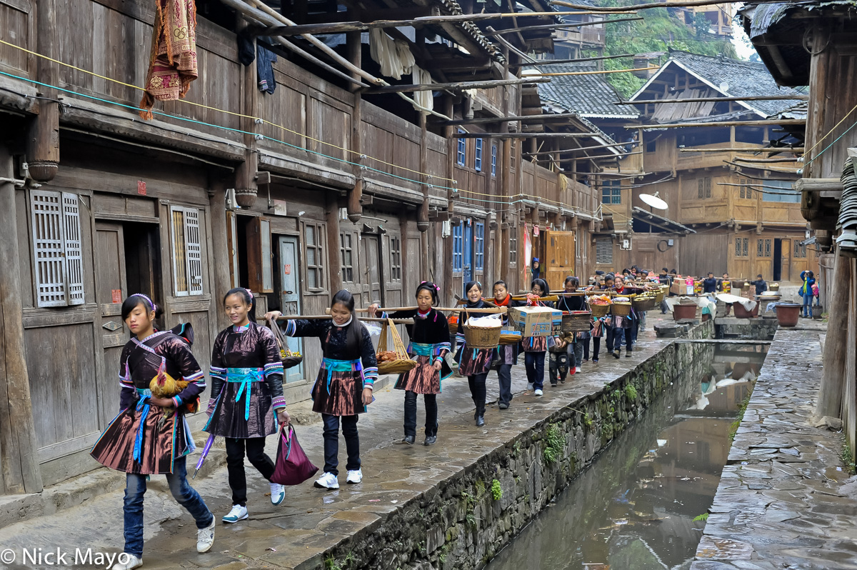 A wedding procession in the Dong village of Yintan on its way to the groom's house, headed by the bride symbolically holding...