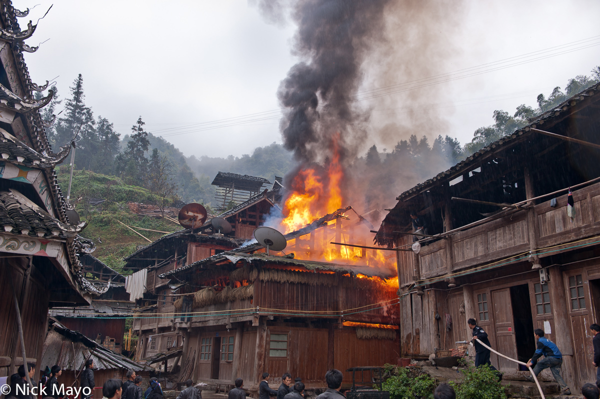A wooden Dong residence on fire in Yintan village.