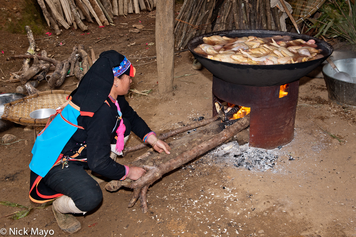 A Yao woman cooking chickens in a wok for a wedding banquet in Hui Yang Lao Zai.