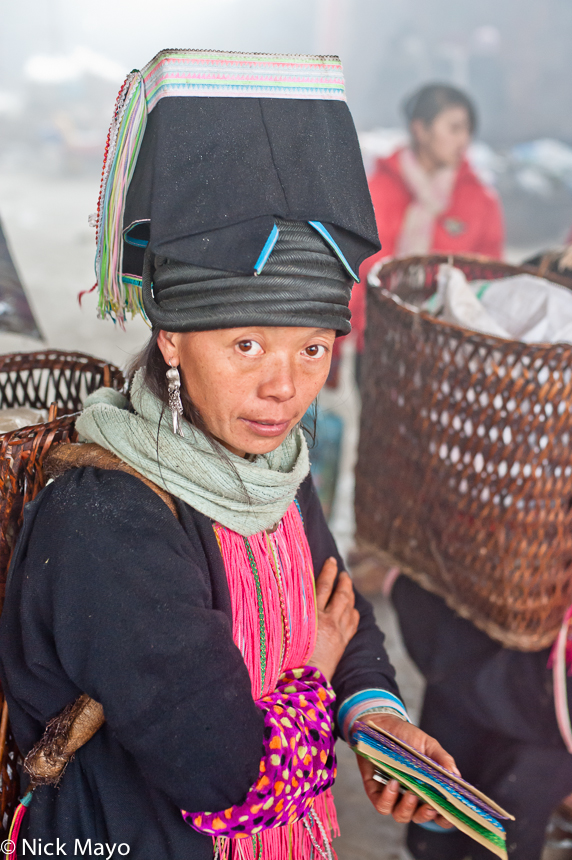 A Pintoh Yao women, in a traditional flat topped hat, shopping in Pinghe market.