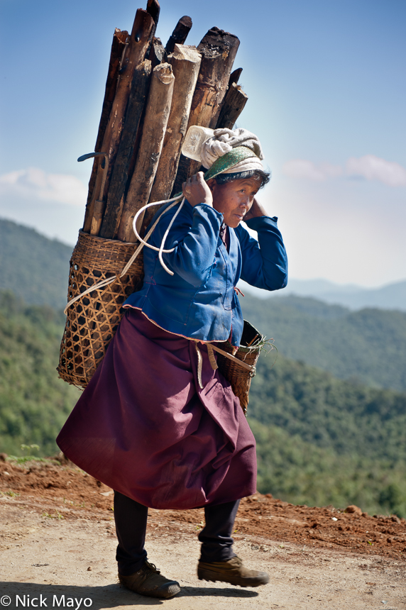 A Bulang woman using a backstrap basket to carry firewood home to Xinnan.