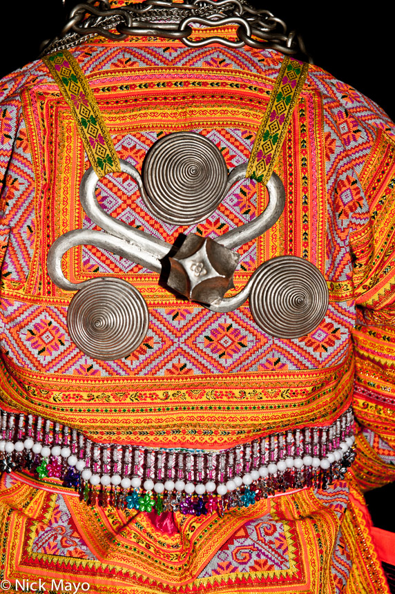 A Miao girl wearing a three spiralled back piece at a wedding in Cenzui.