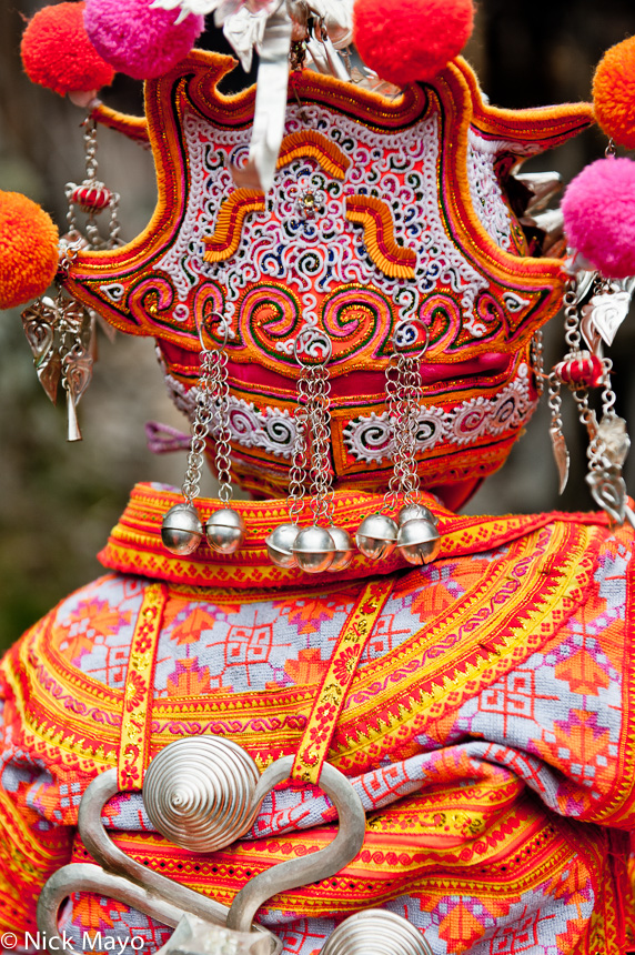 A baby dressed in an ornate hat and backpiece at a Miao wedding in Cenzui.