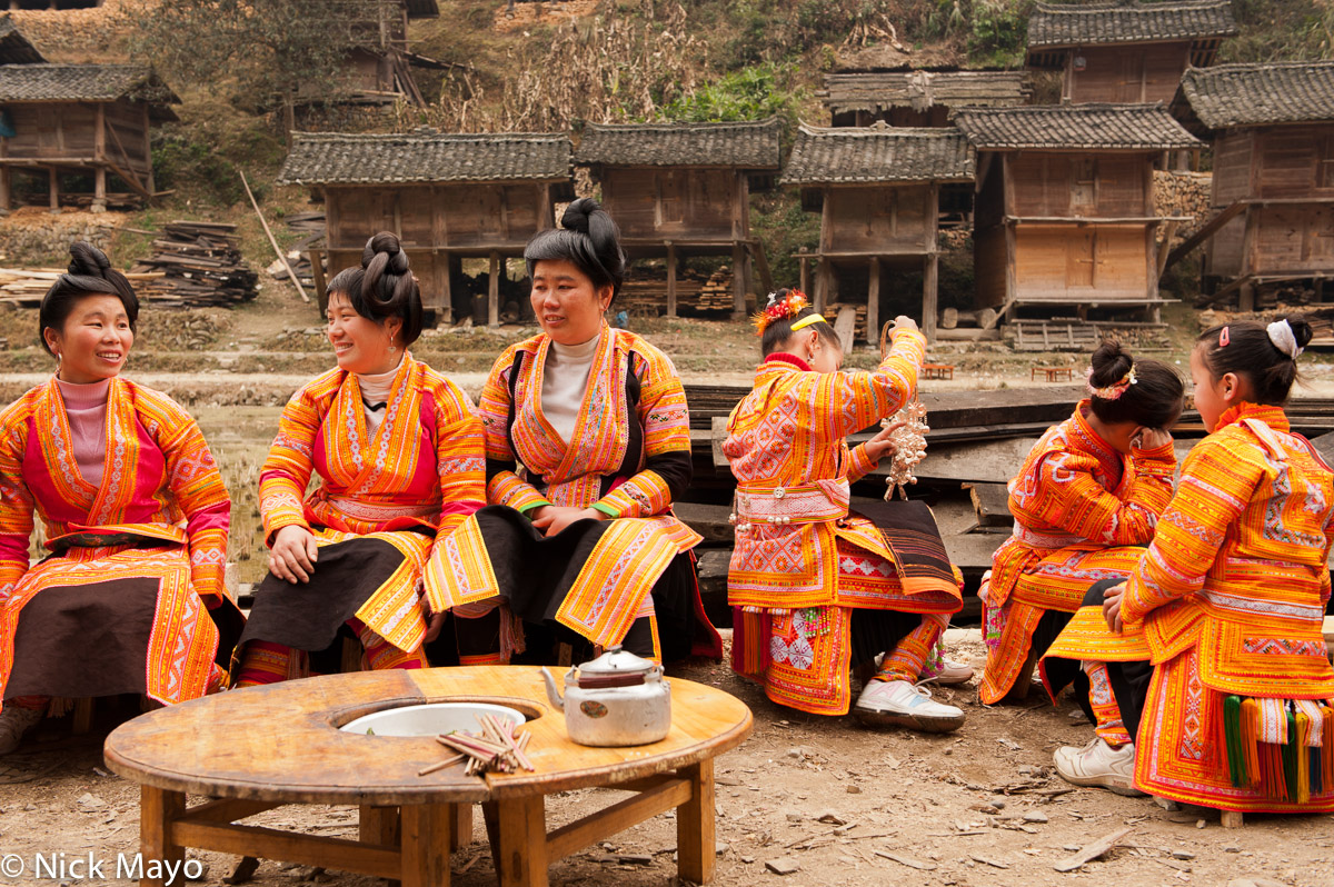 A Cenzui Miao group attired in orange festival clothes and black aprons awaiting a wedding lunch.