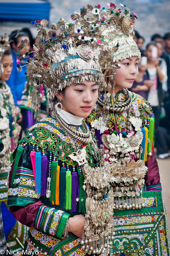 Two unmarried Dong girls wearing crown headdresses, breastpieces and silver necklaces at a New Year festival in Yang Dong.