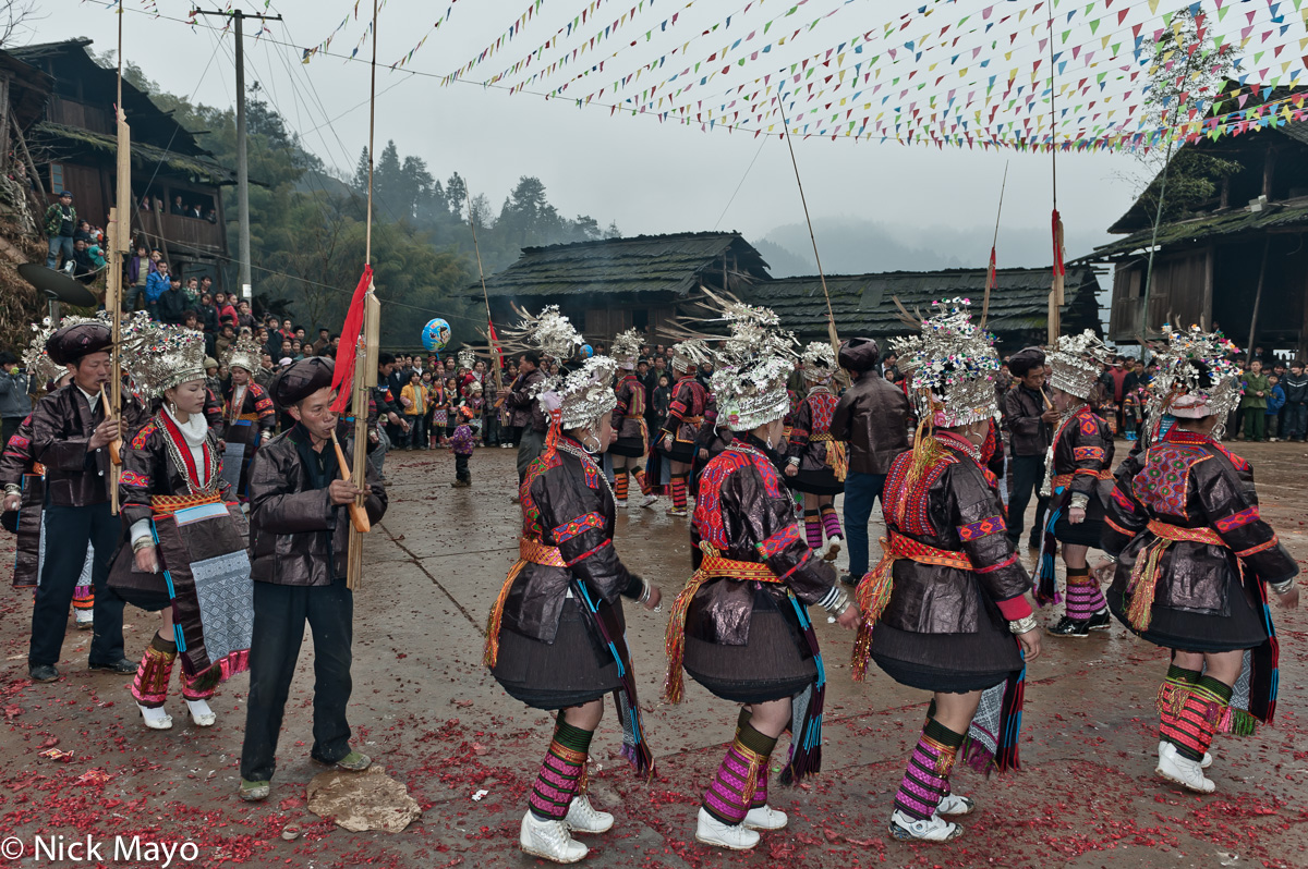 Unmarried mini skirted Miao girls circling with the lusheng pipers at a New Year festival in Ba Shu.