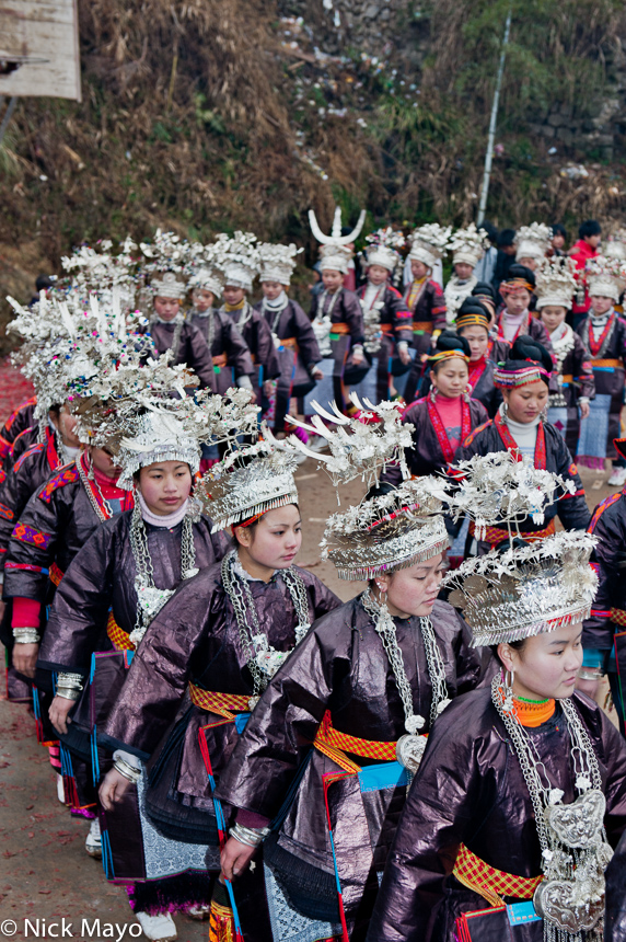 Unmarried mini skirted Miao girls, wearing festival attire of crown headdresses, breastpieces, embroidered aprons and leggings...