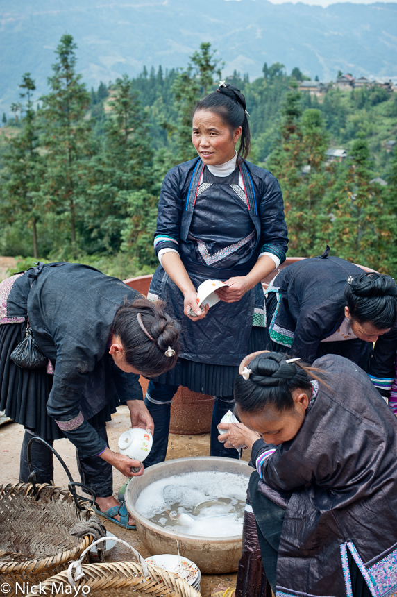 Traditionally dressed black Miao ladies washing up after a housewarming banquet in Chai Li.