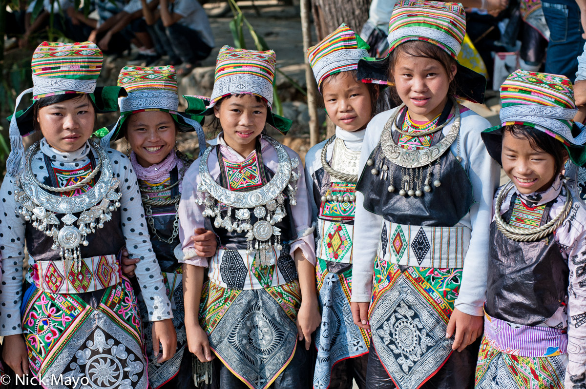 Six Miao girls from Yangweng village wearing festival attire of embroidered aprons, hats, waist bands and necklaces. 