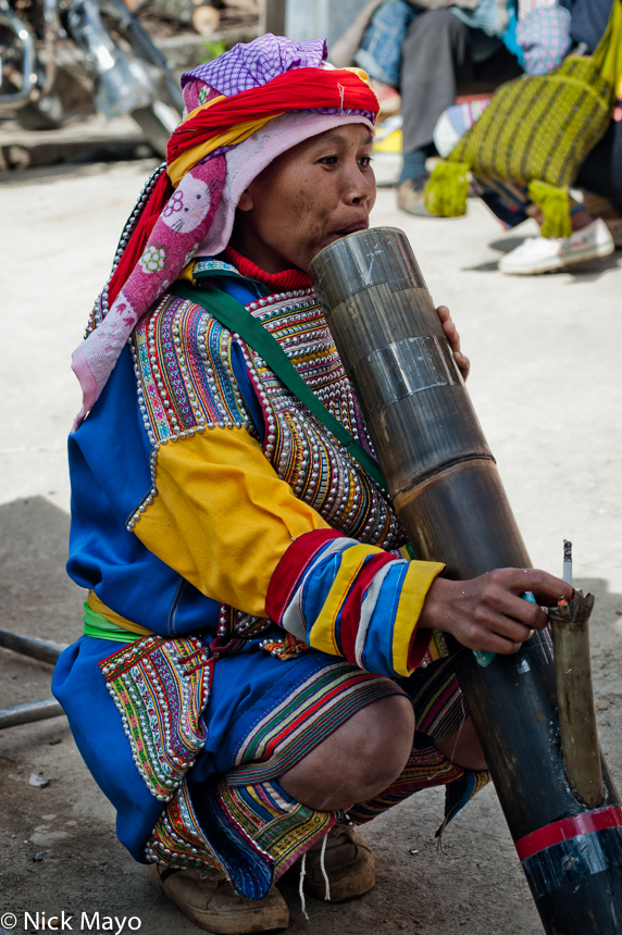 A Lahu woman smoking a cigarette through a bamboo water pipe at Nanmei market.