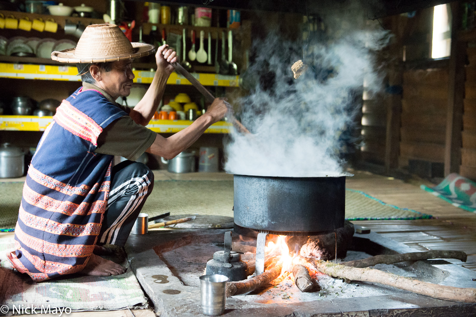 An Idi Mishmi tribesman cooking on the hearth in his home at Hunli.