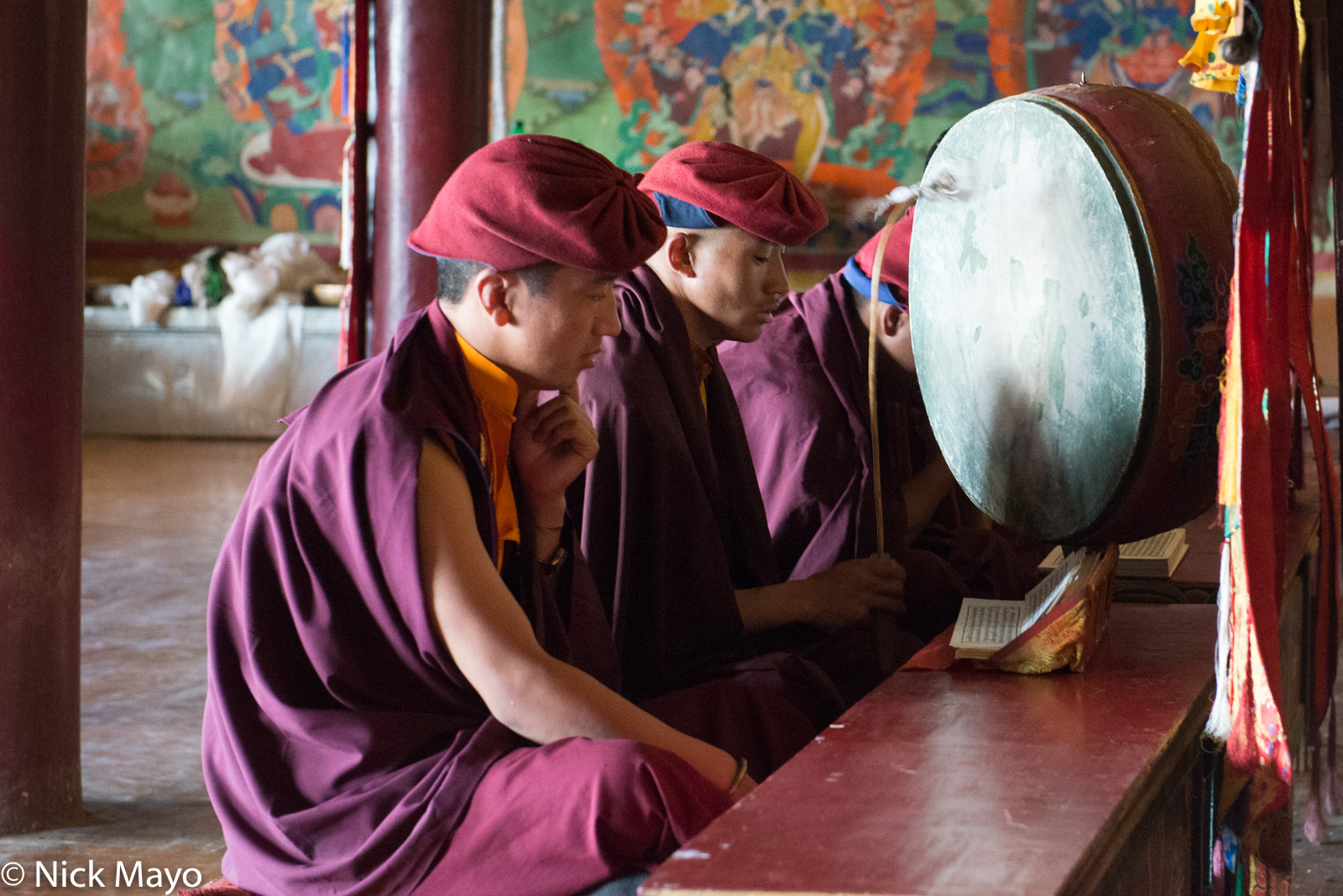 Changpa monks chanting from a scripture and beating a sacred drum at Korzok monastery.